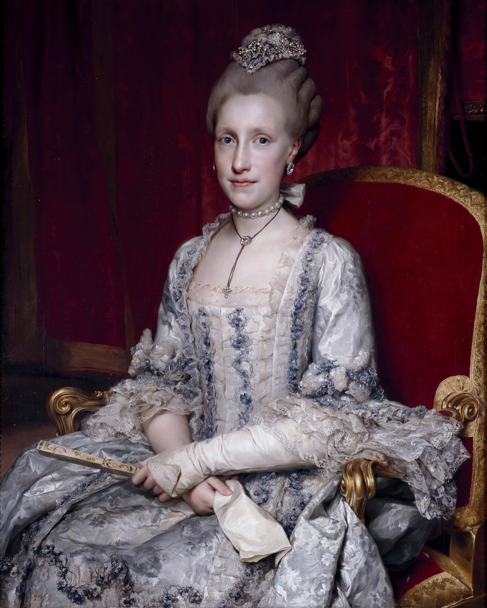 Retrato da Rainha Carlota pintado por Anton Raphael Mengs, mostrando uma mulher sentada em uma poltrona vermelha, vestindo um suntuoso vestido branco e azul com rendas, adornada com joias e uma coroa, em um estilo neoclássico.