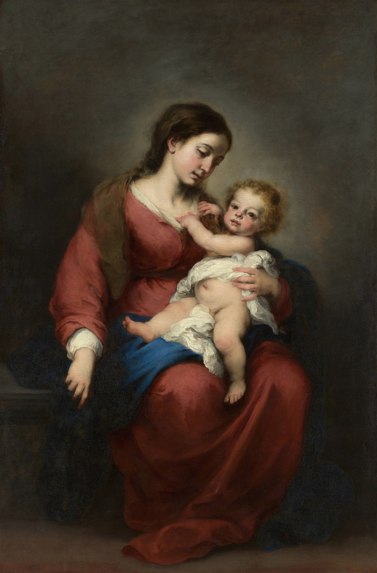 Quadro decorativo 'A Virgem e o Menino' de Bartolomé Estebán Murillo, mostrando Maria em um vestido vermelho e manto azul segurando o Menino Jesus em seu colo. A cena é pintada em tons escuros e ricos, com a luz focando nas figuras.