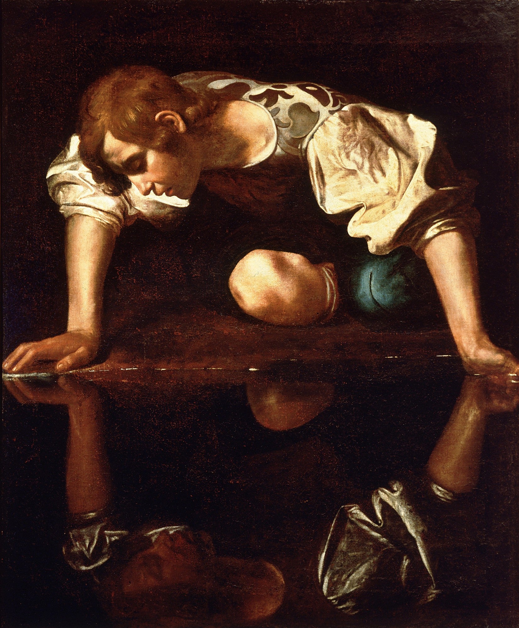 Pintura a óleo de Caravaggio, 'Narciso', mostrando um jovem ajoelhado, debruçado sobre a água escura, observando seu próprio reflexo. A luz incide sobre seu rosto e braços, contrastando com o fundo escuro. Um vaso está ao lado do jovem.