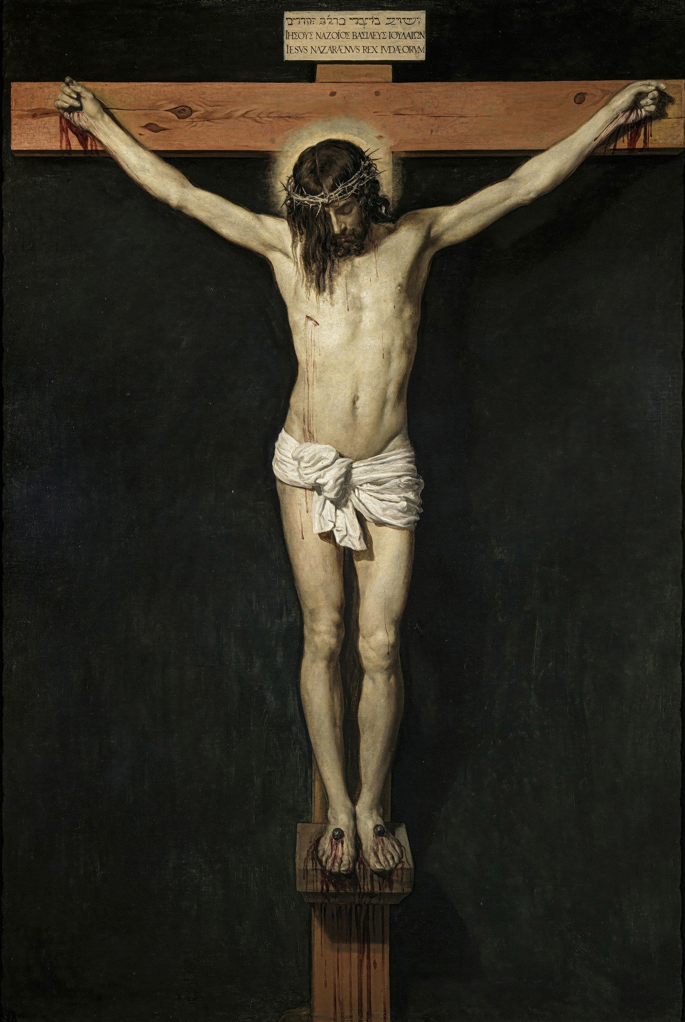 Quadro decorativo do Cristo Crucificado de Velázquez, apresentando a figura de Cristo pregado na cruz com um fundo escuro, destacando o corpo em tons claros e a coroa de espinhos, com sangue escorrendo nas mãos e pés.