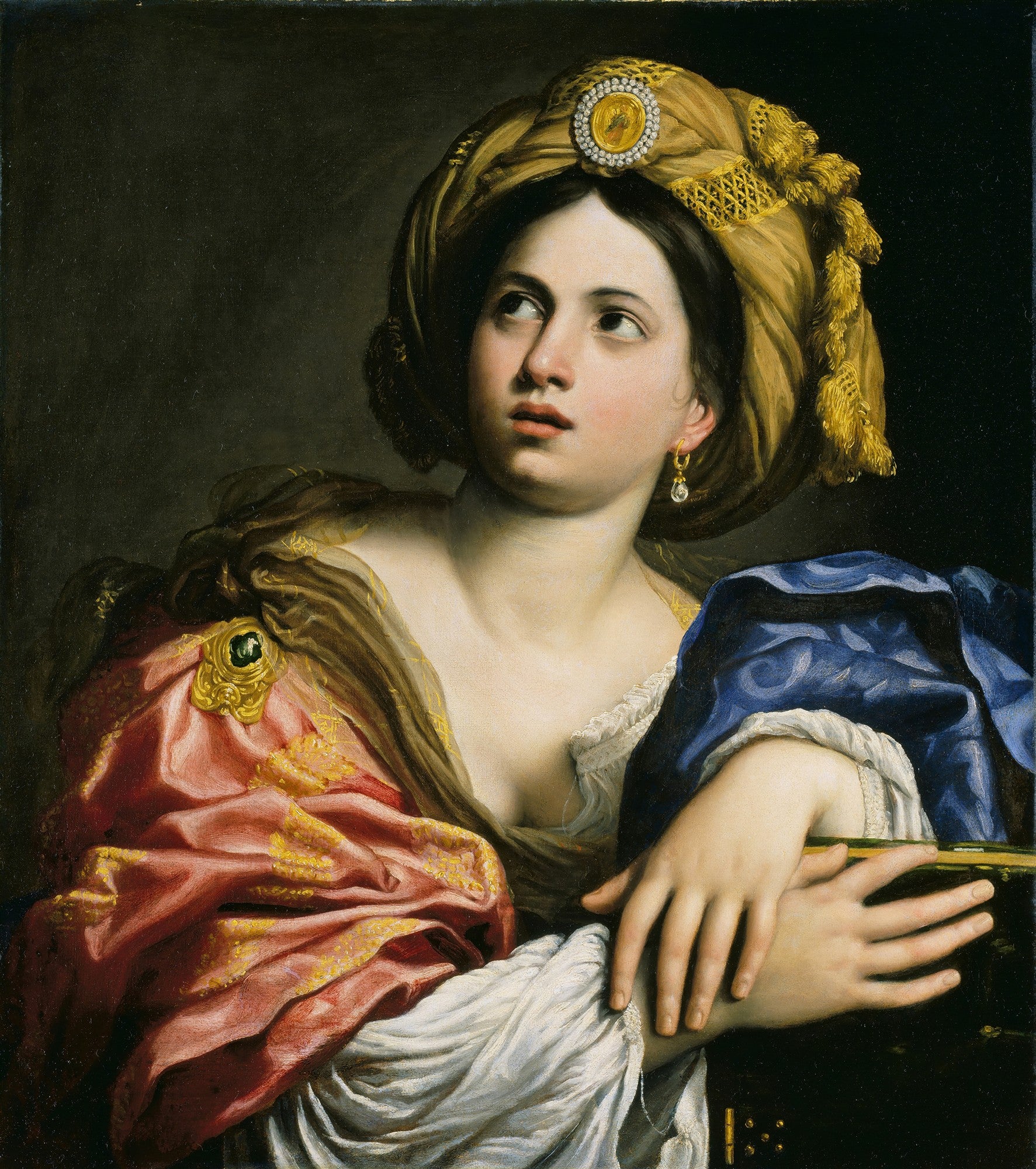 Retrato de busto de uma mulher jovem, a Sibila Persa, olhando para cima com expressão pensativa, usando um turbante dourado e vestes coloridas. Pintura a óleo de Domenichino Zampieri.