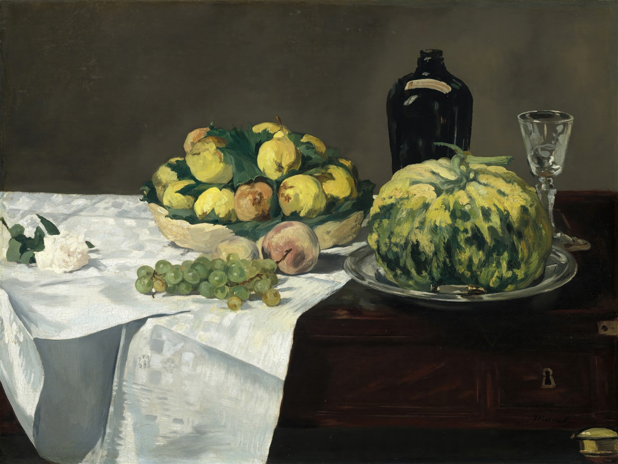 Quadro decorativo apresentando uma natureza-morta de Edouard Manet com uma cesta de frutas, uvas, um pêssego, um melão, uma garrafa escura, um copo de vidro e uma rosa branca sobre uma toalha de mesa branca, em uma superfície de madeira escura.