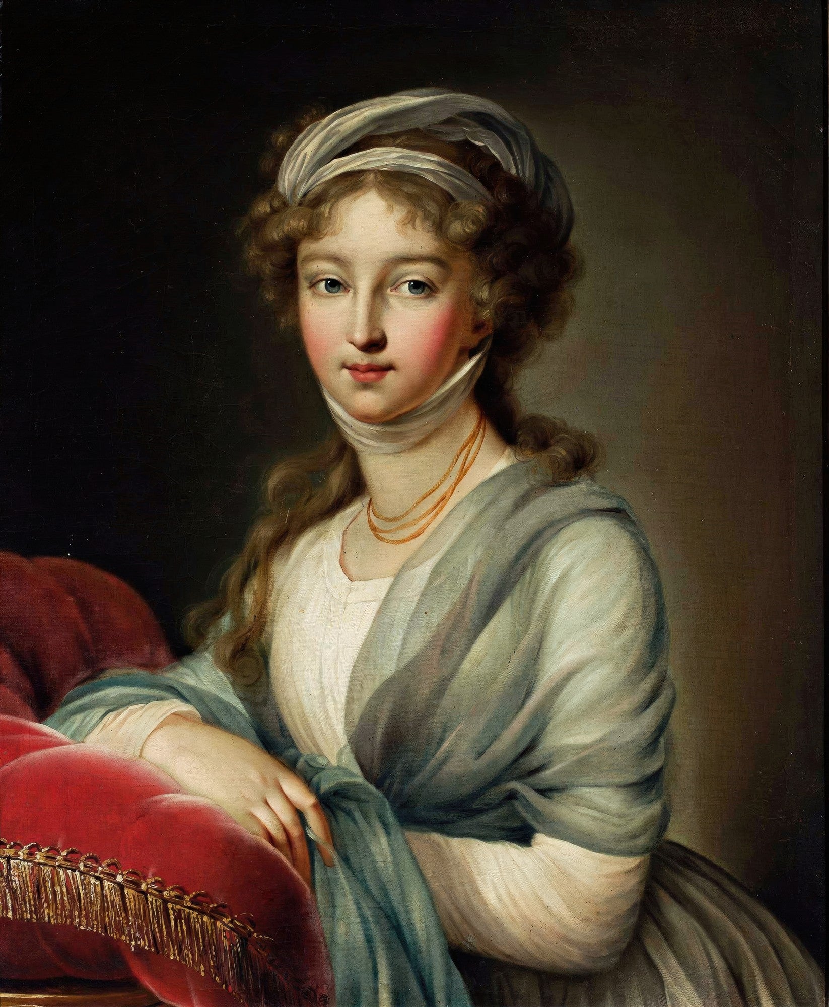 Retrato clássico de uma jovem mulher com cabelos cacheados e laço branco na cabeça, vestindo um xale azul e blusa branca, apoiada em um travesseiro vermelho. Obra de Elisabeth Louise Vigée Le Brun.