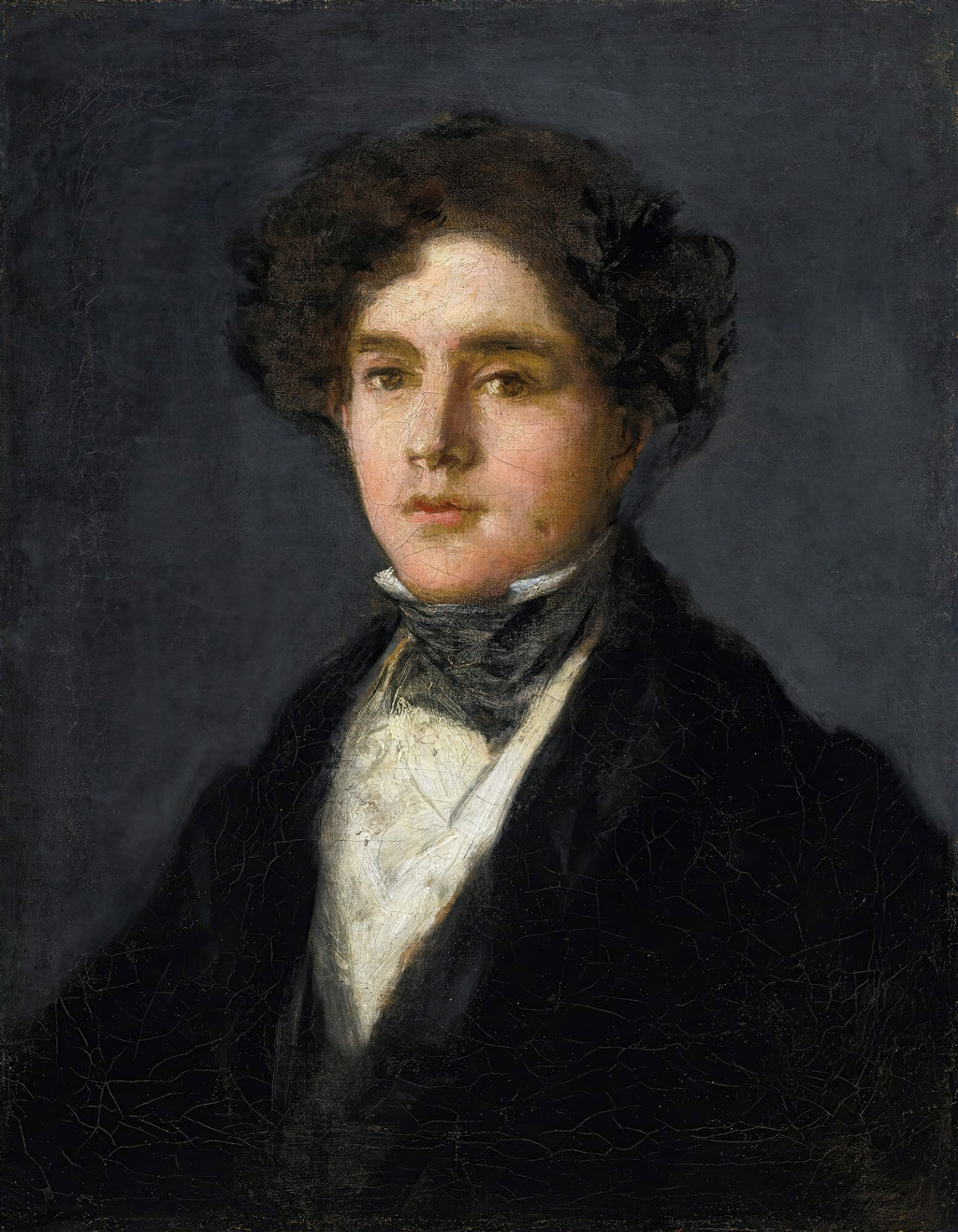 Retrato de um jovem de cabelos escuros e ondulados, vestindo um casaco escuro e camisa branca, com olhar direto e expressivo, em fundo cinza-escuro. Obra atribuída a Francisco de Goya.