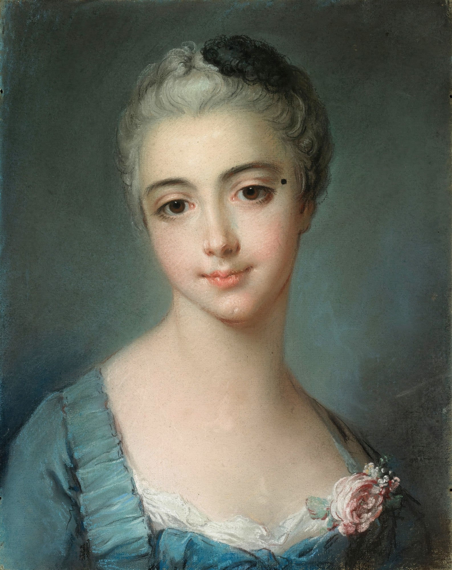 Retrato de uma mulher jovem, de pele clara e cabelos escuros, vestindo um vestido azul com detalhes florais. A obra é atribuída a François Boucher e exibe tons suaves de azul, rosa e branco.