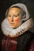 Retrato de uma mulher do século XVII, atribuído a Frans Hals, com touca branca e gola de renda frisada. A mulher tem pele clara, bochechas rosadas e veste um corpete escuro com detalhes em vermelho bordô. O fundo é escuro e liso, destacando a figura central.