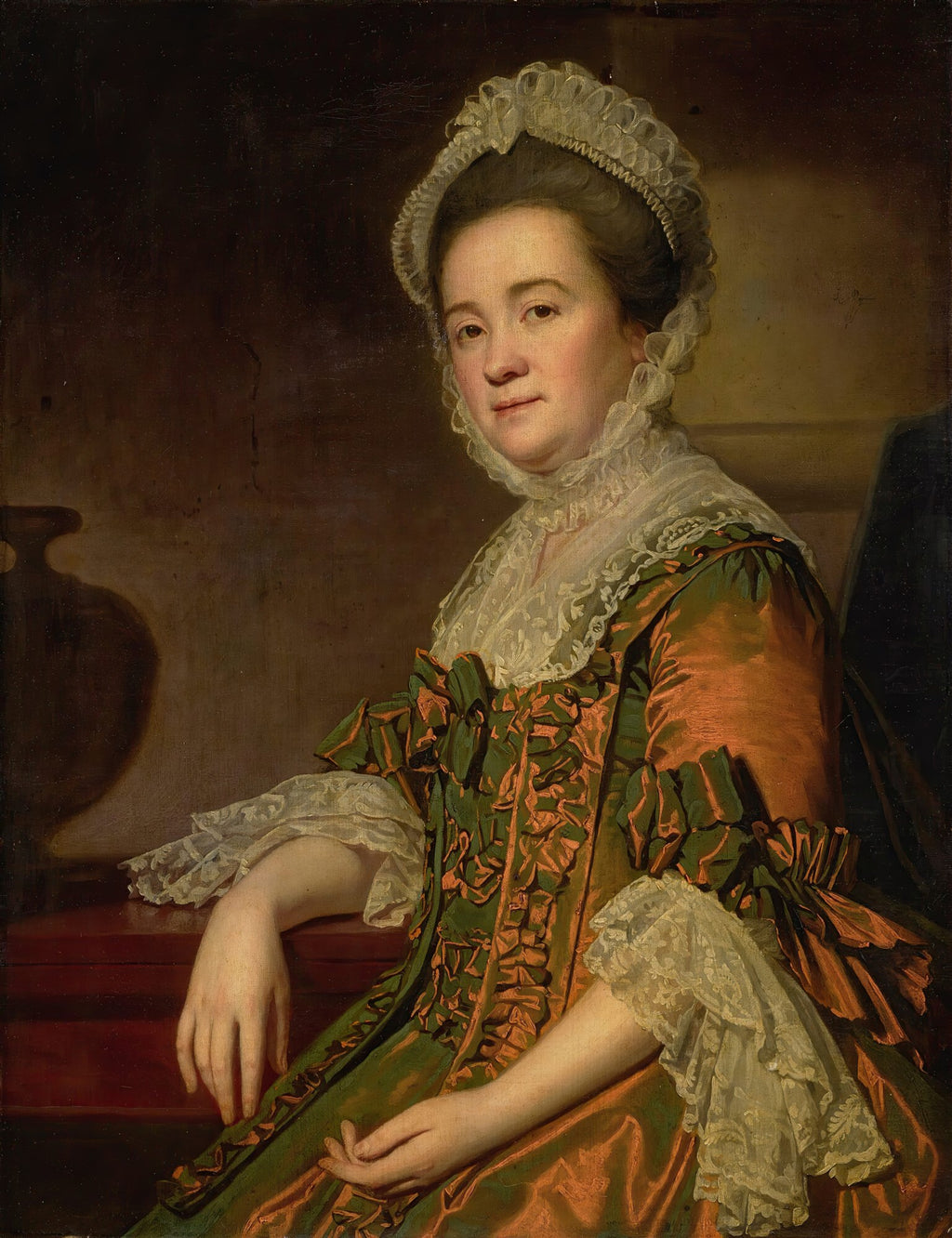 Retrato de uma senhora com chapéu de renda e vestido verde e laranja, atribuído a George Romney. A senhora está sentada, com o braço esquerdo apoiado em uma superfície vermelha, e olha diretamente para o observador.