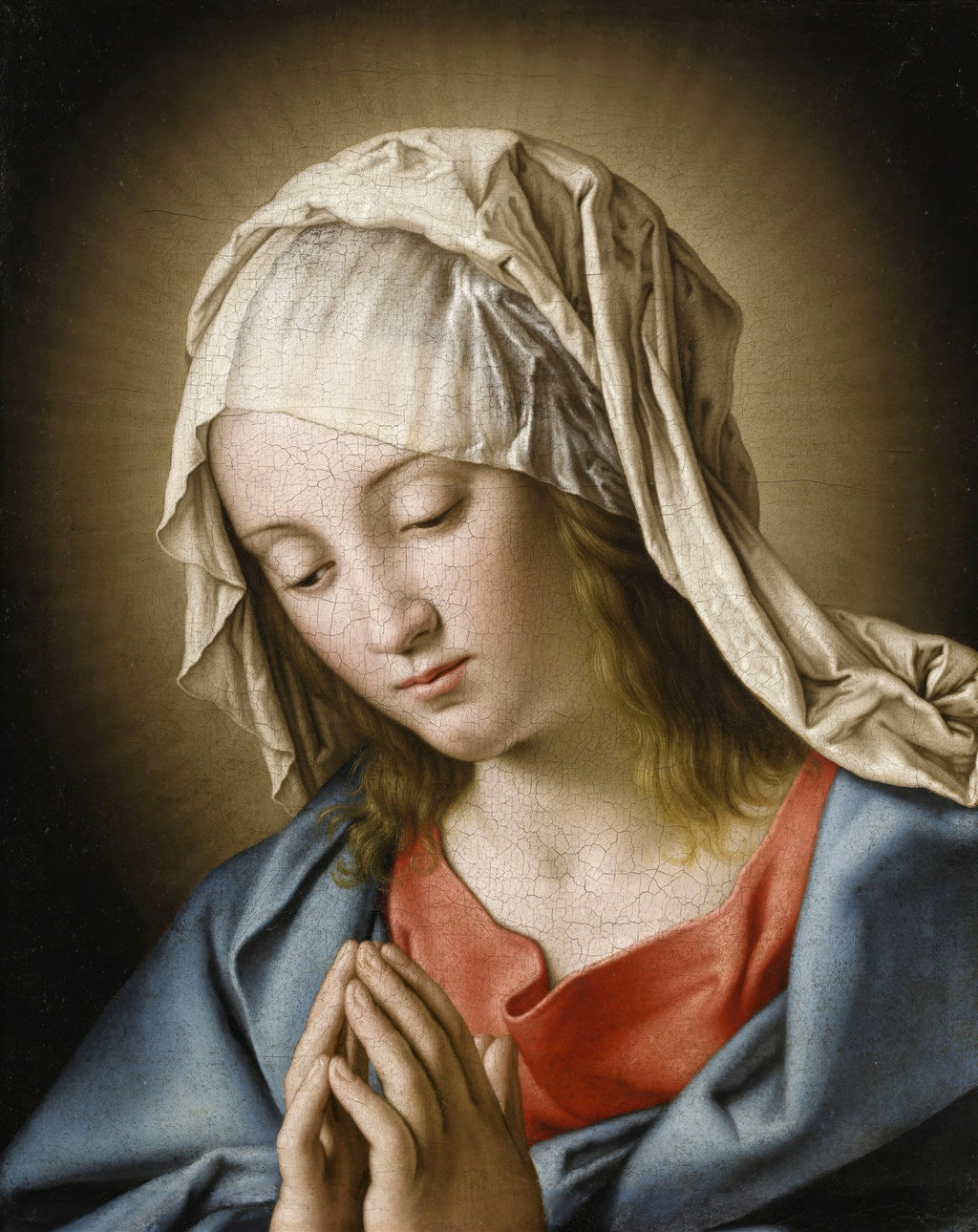 Quadro decorativo da pintura 'A Virgem em Oração' de Sassoferrato, mostrando o rosto sereno de uma mulher com véu branco, vestes azuis e vermelhas, e mãos unidas em prece, com fundo escuro. A imagem apresenta textura de craquelê na superfície.