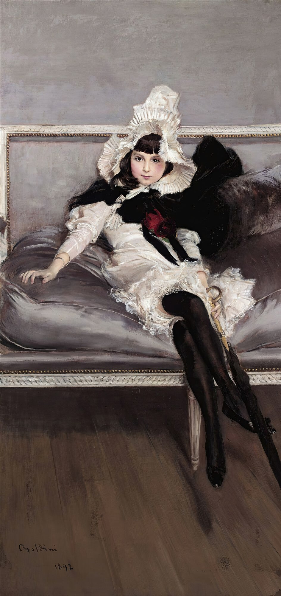 Retrato de uma mulher jovem sentada em um sofá, vestindo um chapéu branco rendado, blusa branca com detalhes rendados, uma capa preta e meias pretas. Ela segura um guarda-chuva. A obra é de Giovanni Boldini, de 1892.