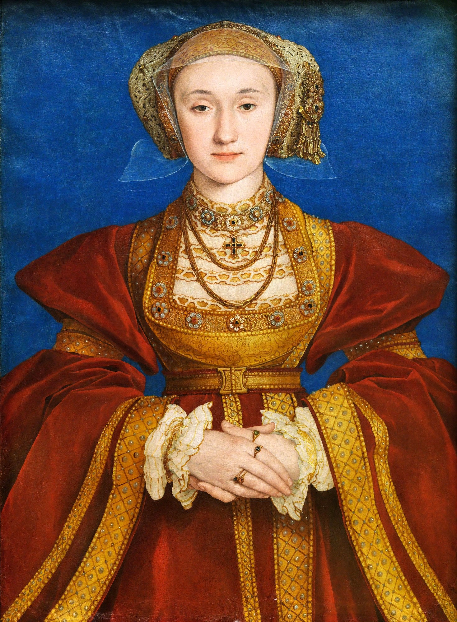 Retrato de Ana de Cleves por Hans Holbein, o Jovem. A imagem mostra uma mulher jovem com touca dourada e véu transparente, vestindo um vestido suntuoso em tons de vermelho e dourado, com joias elaboradas, contra um fundo azul sólido. Suas mãos estão elegantemente cruzadas à frente.