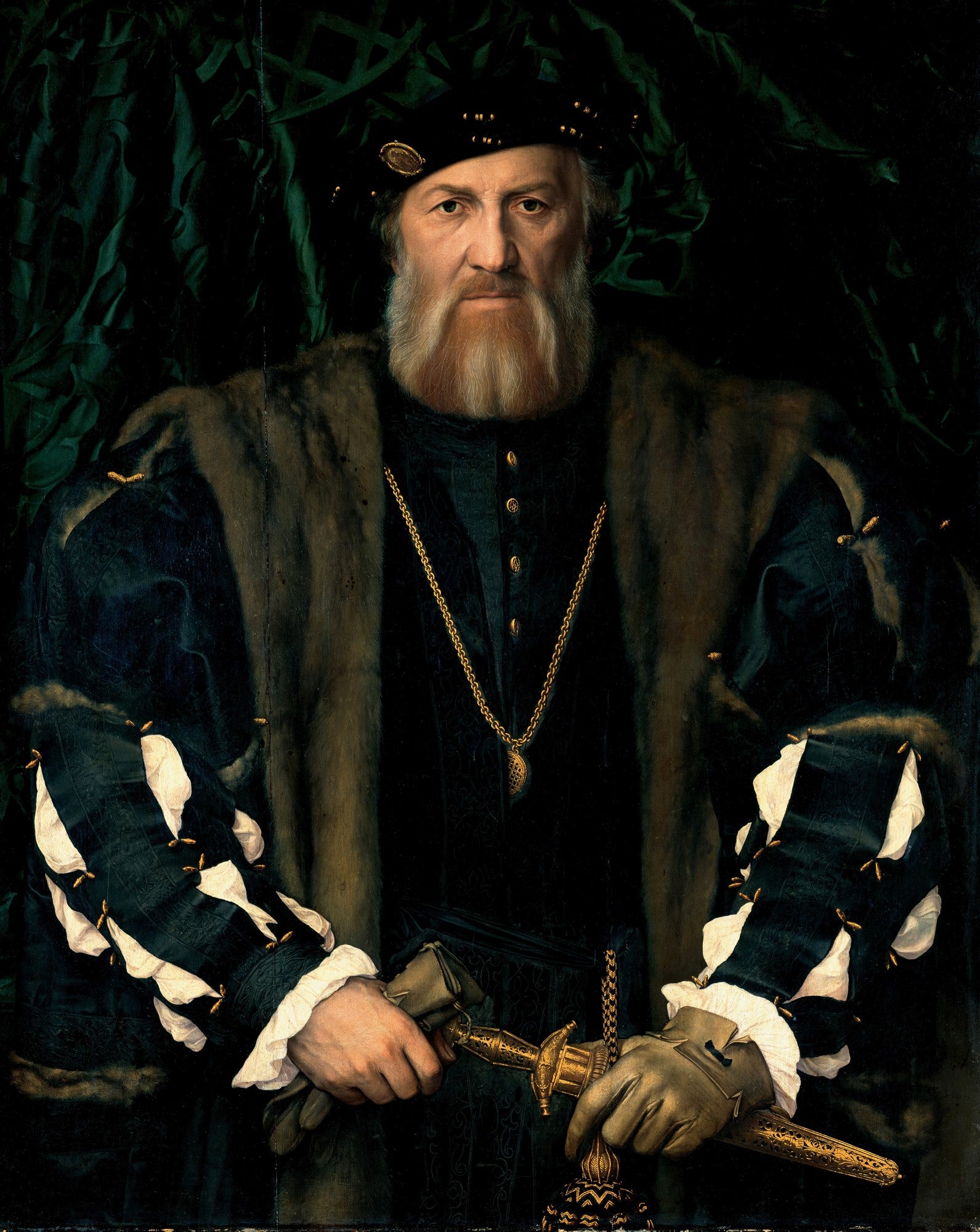 Retrato renascentista de um homem com barba ruiva e chapéu escuro, vestindo roupas suntuosas com um colar dourado e segurando uma adaga, contra um fundo verde-escuro. Obra atribuída a Hans Holbein.
