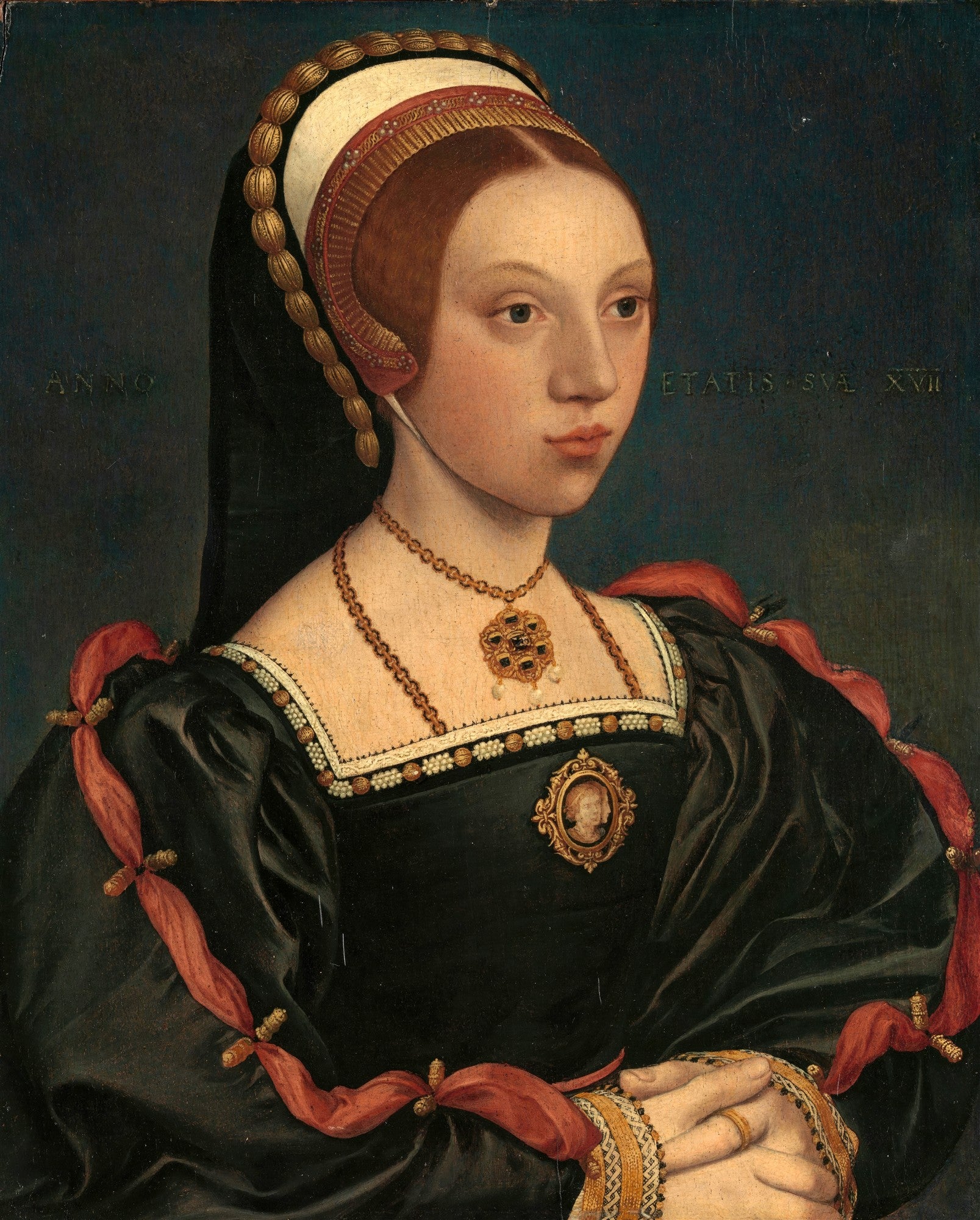 Retrato de uma jovem mulher do século XVI, atribuído a Hans Holbein, o Jovem, vestindo roupas escuras e joias, com um fundo azul escuro. A mulher tem cabelos ruivos e uma expressão serena.