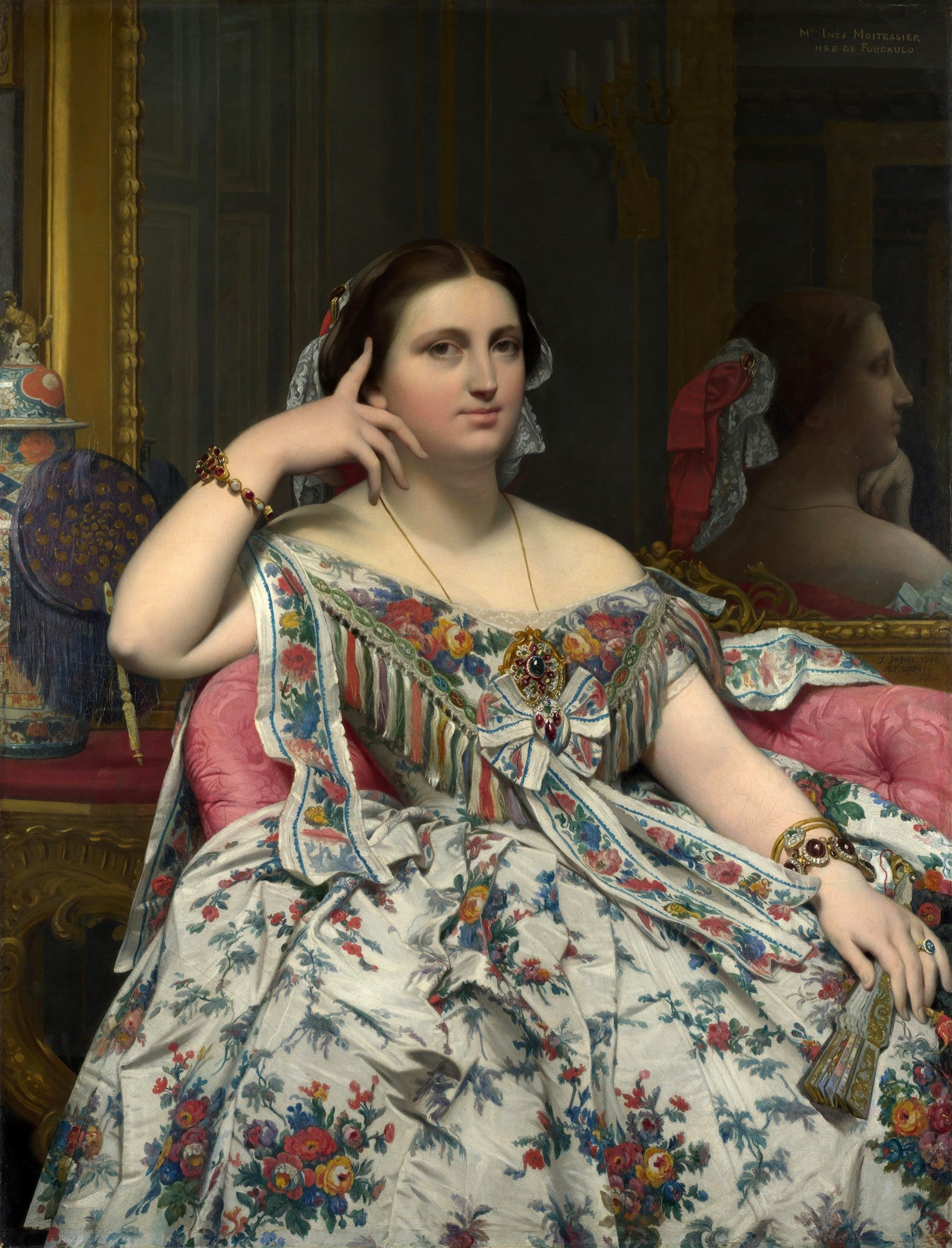 Retrato de Madame Inès Moitessier sentada, obra de Jean-Auguste-Dominique Ingres. A mulher veste um luxuoso vestido floral com detalhes em laço e franjas, possuindo joias e um penteado clássico. Ao fundo, um espelho reflete sua imagem de perfil. A paleta de cores é rica, com tons de branco, vermelho, azul e dourado.