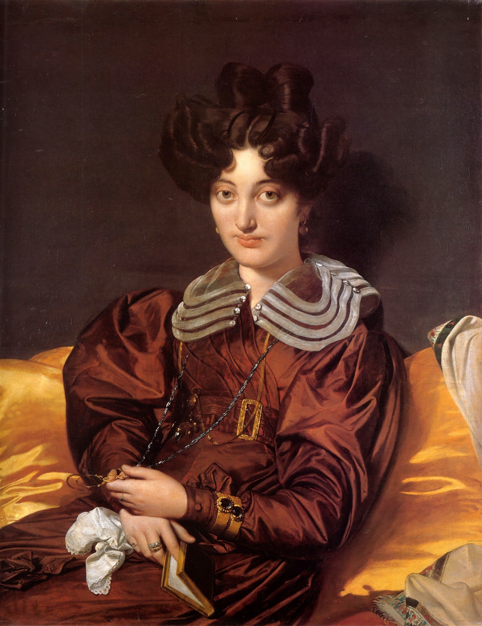 Retrato de Madame Rivière, obra de Jean-Auguste Dominique Ingres. Uma mulher com penteado elaborado, vestido de seda marrom-avermelhada, colar e joias, sentada em um sofá amarelo. A imagem transmite uma sensação de elegância e serenidade, com atenção aos detalhes dos tecidos e da expressão facial.