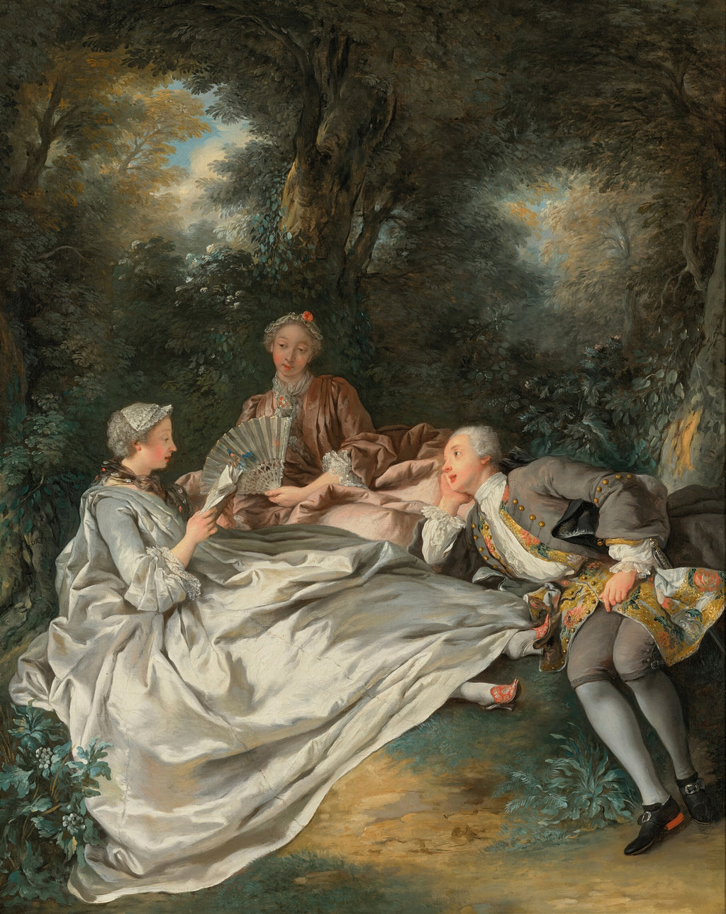 Quadro decorativo 'A Leitura' de Jean François de Troy, representando uma cena galante Rococó com três figuras elegantemente vestidas lendo em um ambiente campestre, com árvores e folhagem ao fundo. Uma mulher de vestido claro segura um leque, outra de vestido marrom observa, e um homem de casaco cinza com detalhes dourados as corteja.