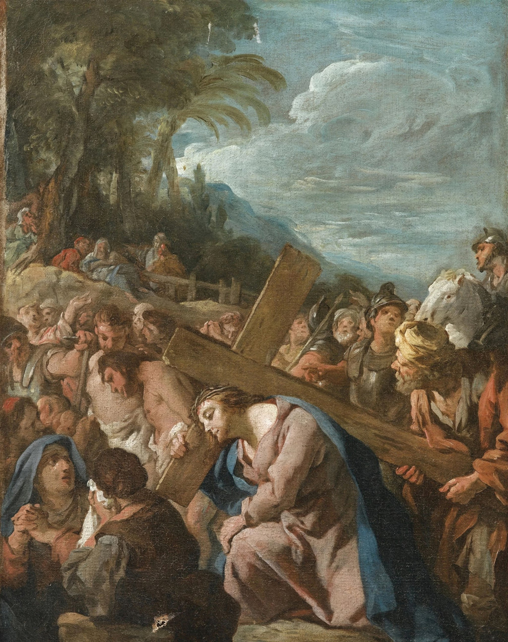 Pintura a óleo de Jean François de Troy, 'A Caminho do Calvário', mostrando Jesus Cristo carregando a cruz, cercado por uma multidão e soldados romanos, com paisagem montanhosa e céu dramático ao fundo. A obra apresenta tons terrosos, azuis e cinzas.