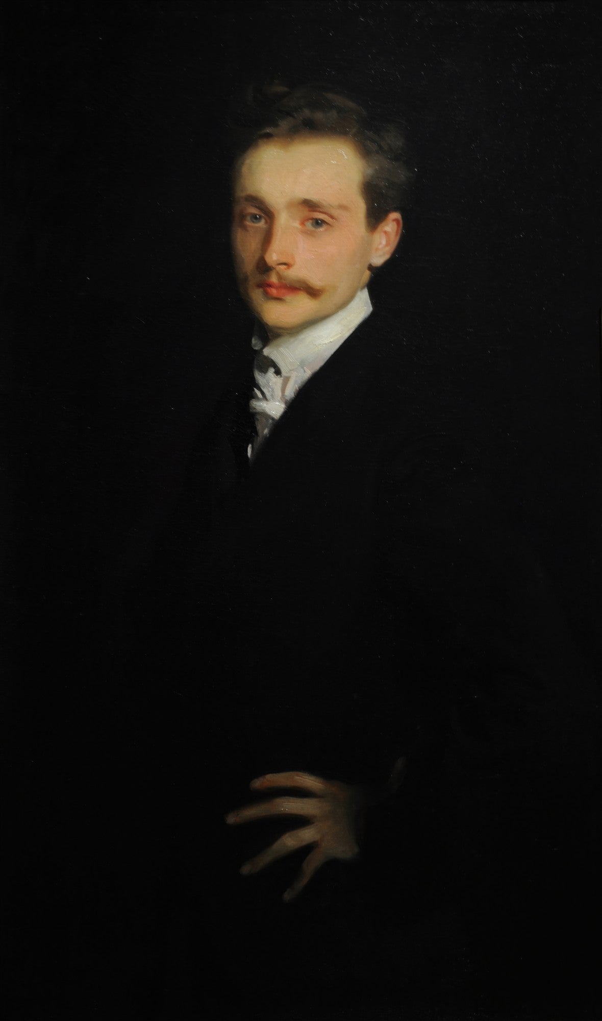 Retrato a óleo de um homem jovem com bigode, vestindo traje formal escuro e camisa branca, em um fundo totalmente preto. A luz incide sobre seu rosto e mão, criando um contraste dramático.