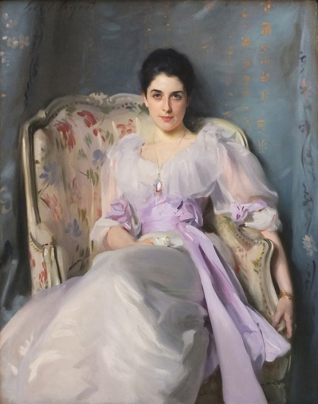 Retrato a óleo de Lady Agnew of Lochnaw por John Singer Sargent, com uma mulher sentada em uma poltrona floral, vestindo um vestido branco e lilás, com um colar pendente. O fundo é um tecido azul com padrões dourados.