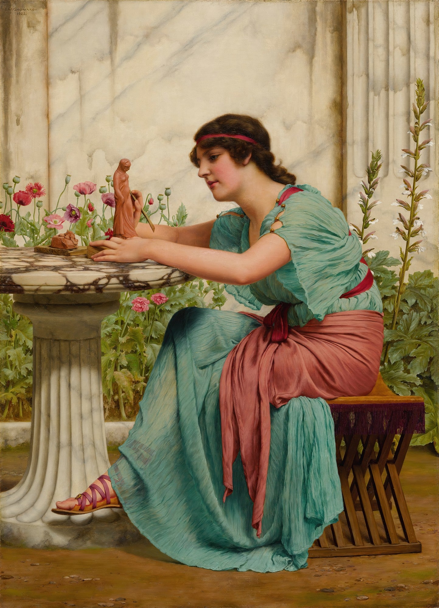 Mulher jovem com vestido azul-esverdeado e faixa vermelha modelando uma estátua de terracota em uma mesa de mármore, em um cenário de jardim com colunas e flores. Obra de John William Godward.
