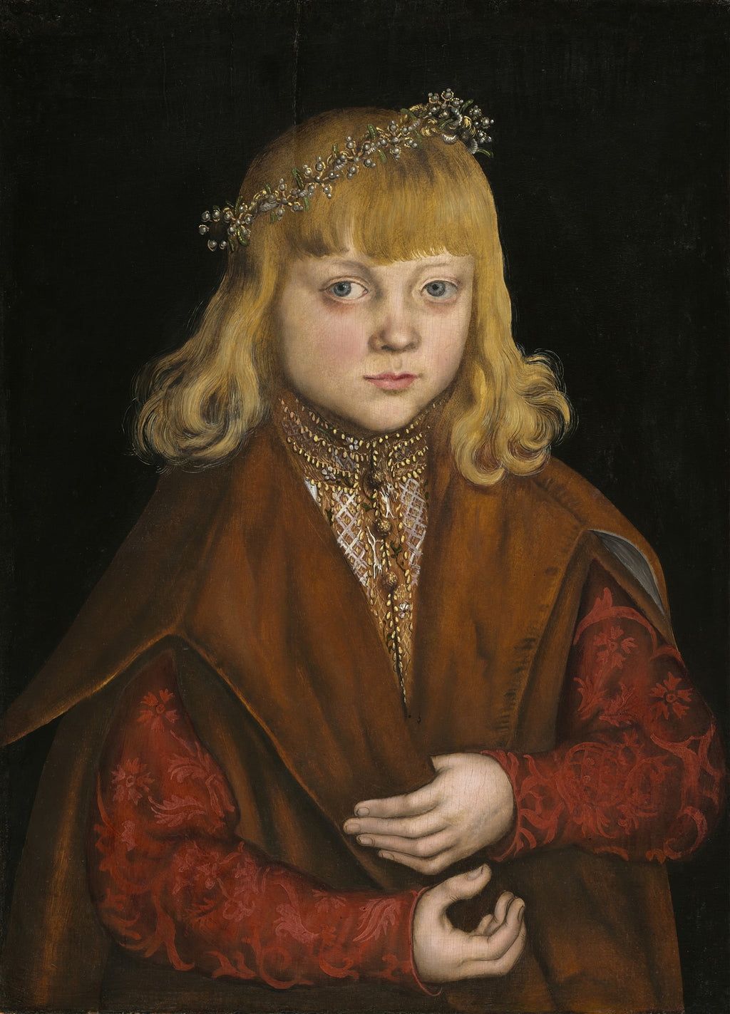 Retrato de um menino com cabelos loiros e coroa de flores, vestindo um traje vermelho e marrom, com fundo escuro. Obra atribuída a Lucas Cranach.