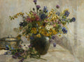Quadro decorativo com natureza morta de Marie Egner. Um vaso rústico repleto de flores silvestres coloridas, como margaridas, cardos roxos, delfínios azuis e flores amarelas, sobre uma mesa ao lado de uma caixa decorada e mais flores soltas.