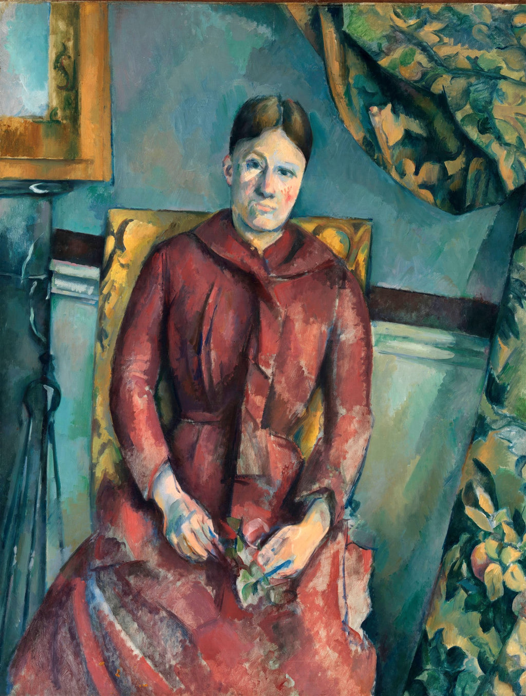 Retrato de uma mulher sentada em uma cadeira amarela, vestindo um vestido vermelho com gola grande, as mãos cruzadas no colo segurando algo verde. O fundo é predominantemente azul esverdeado com detalhes de tecido estampado e um espelho dourado. A pintura é atribuída a Paul Cézanne.