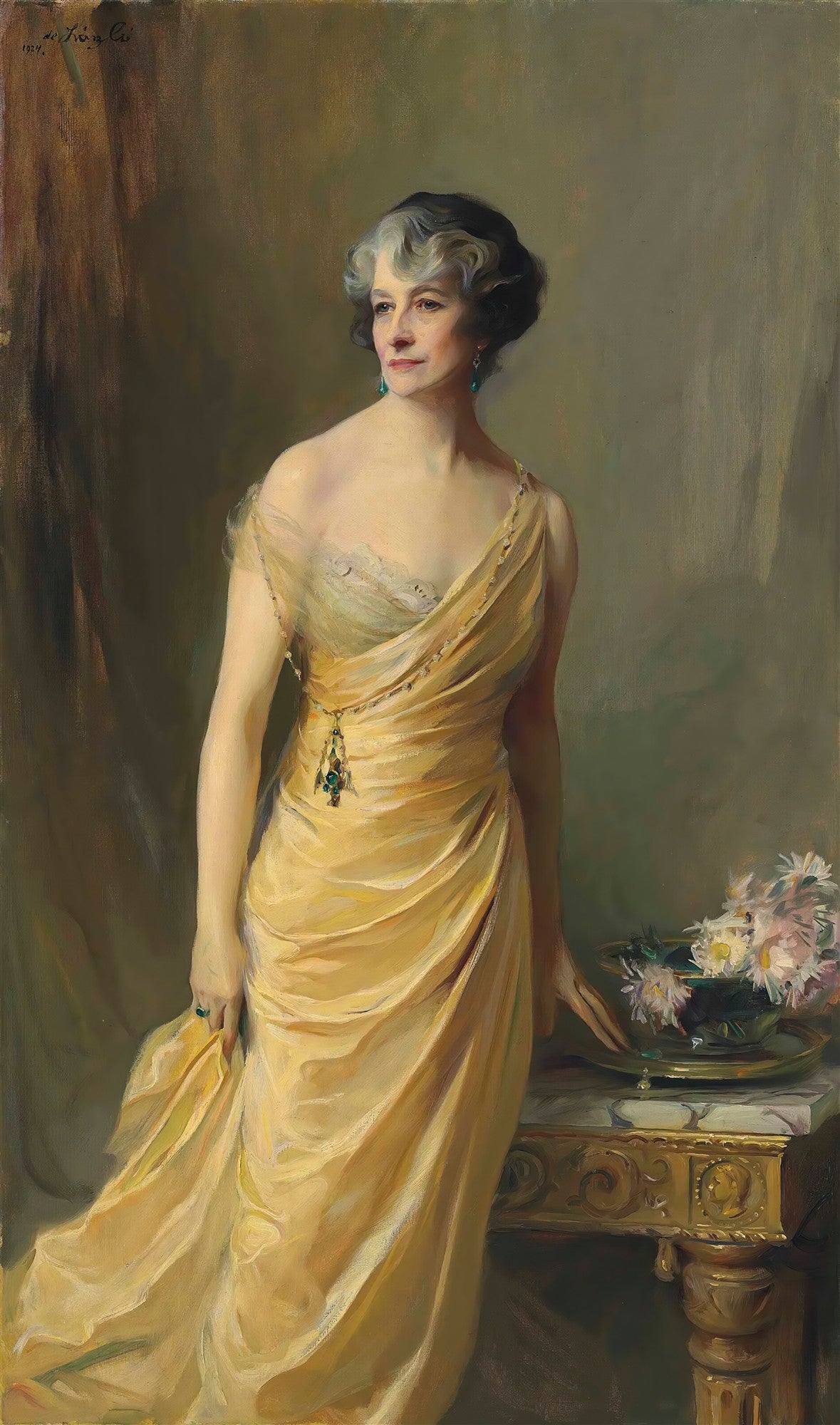 Retrato em óleo de uma mulher elegante de meia-idade, com cabelos grisalhos e um vestido amarelo dourado, assinado por Philip Alexius de László.