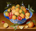 Cesto de frutas cítricas e romãs em uma tigela de porcelana azul e branca sobre uma mesa de madeira. Limões, laranjas e romãs abertas com sementes vermelhas são visíveis, com folhas verdes e flores brancas. A assinatura 'F. I. van Velde' está no canto inferior esquerdo.