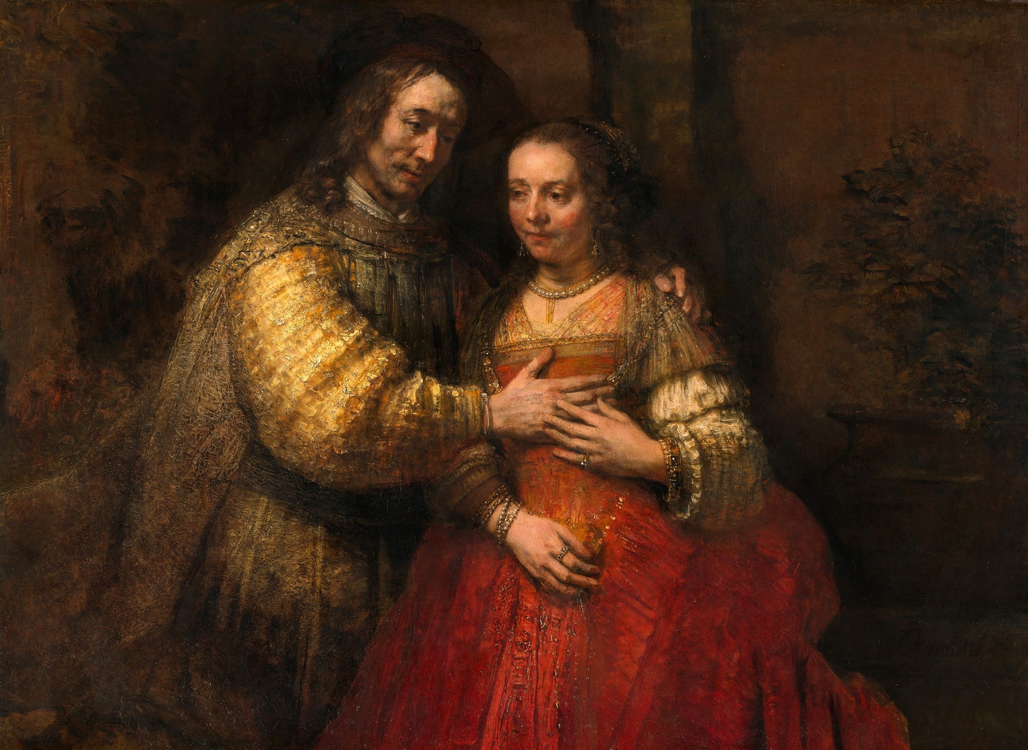 Quadro decorativo 'A Noiva Judia' de Rembrandt, mostrando um casal em um abraço terno, com o homem com a mão no peito da mulher, ambos em trajes ricos em tons de vermelho e dourado, em um fundo escuro.