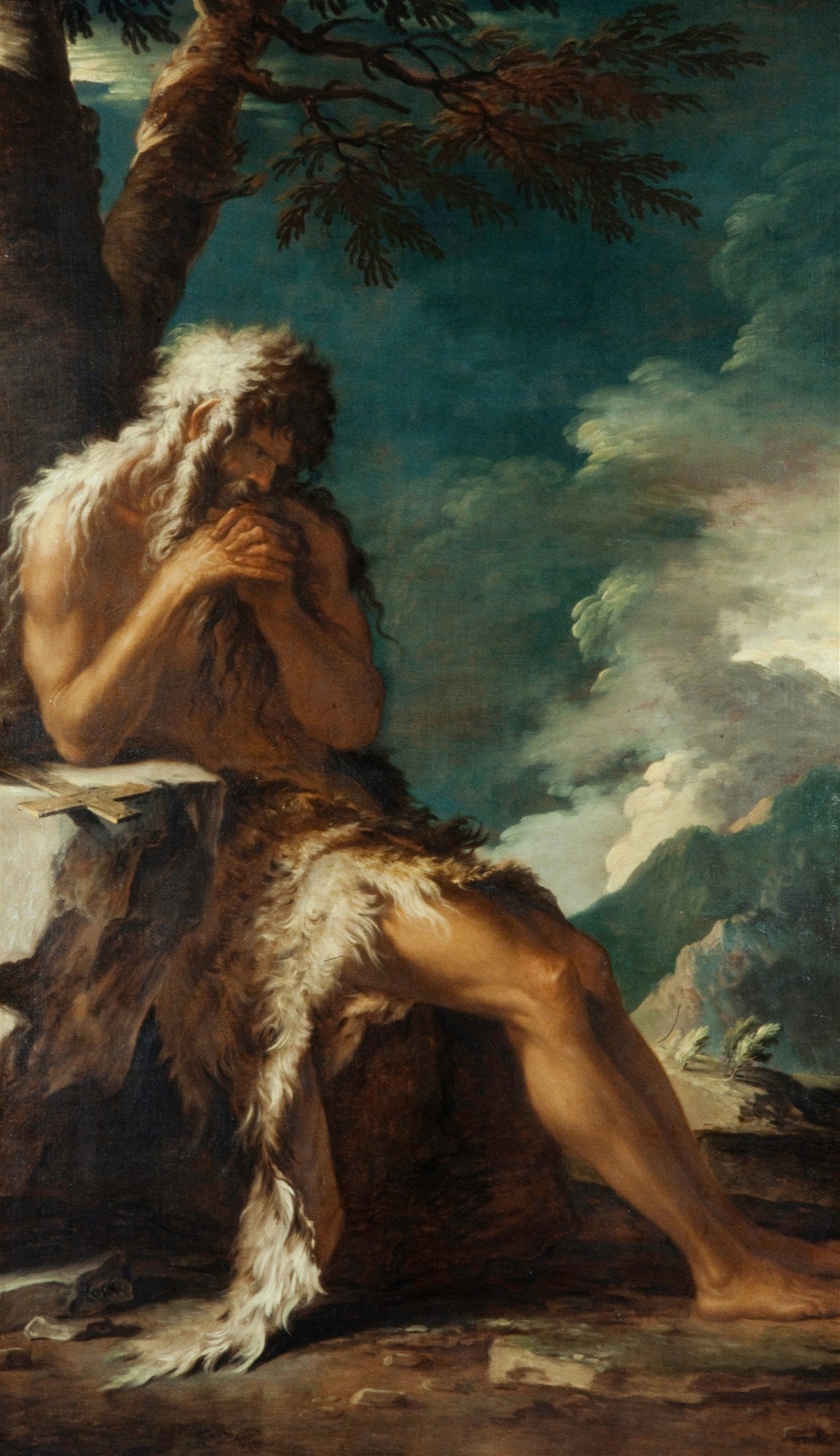 Quadro de São João Batista no Deserto, de Salvator Rosa. A figura barbada e com cabelos longos está sentada sob uma árvore, vestindo pele de animal e com uma cruz rústica ao lado. O fundo é uma paisagem montanhosa com céu dramático e nuvens escuras, evocando solidão e introspecção.