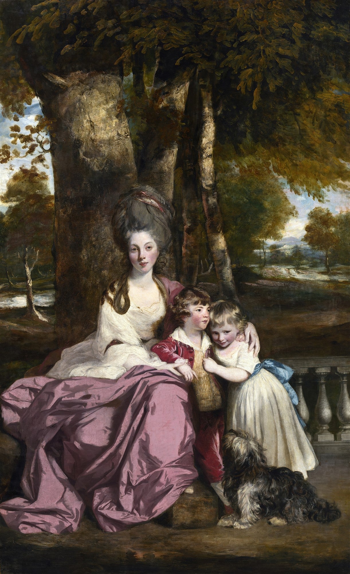 Quadro decorativo retratando uma mulher com um penteado alto e um vestido branco e roxo, sentada sob árvores, abraçando duas crianças e um cachorro, em uma paisagem verde. Obra de Sir Joshua Reynolds.