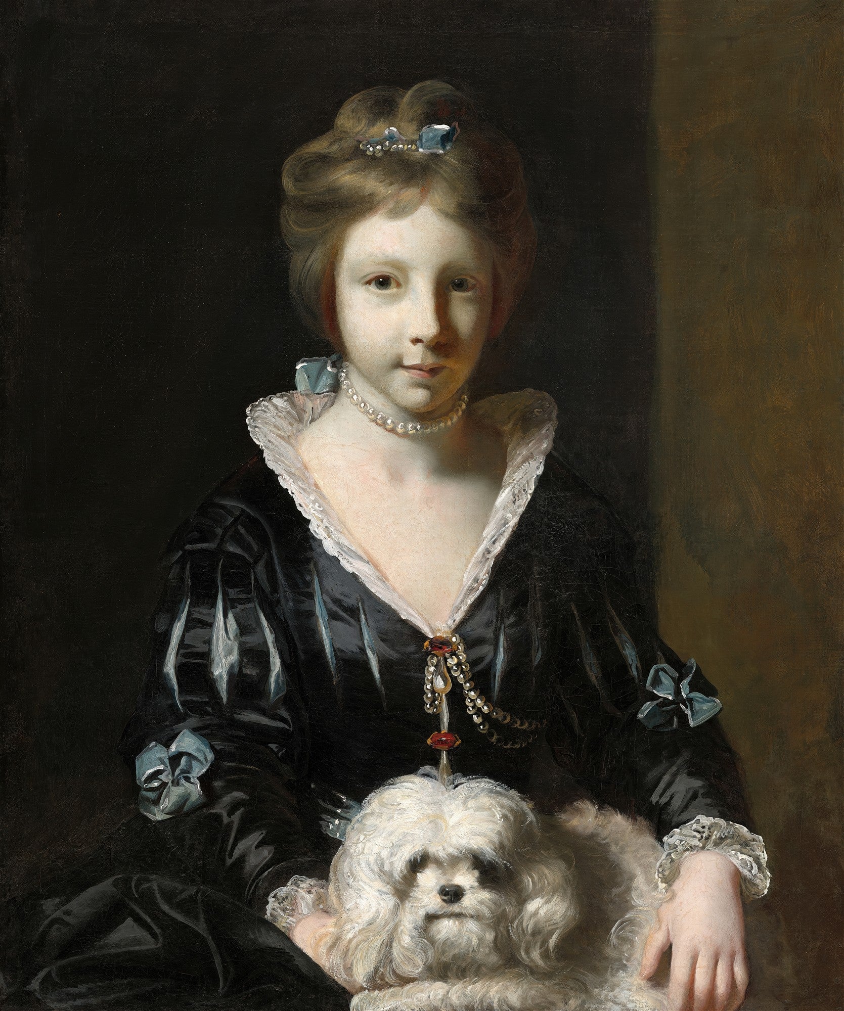Retrato de uma jovem com cabelos castanhos e cachos, vestindo um vestido preto de babados brancos e uma gola de renda, usando um colar de pérolas, segurando um cachorro branco e fofo no colo, em um fundo escuro.