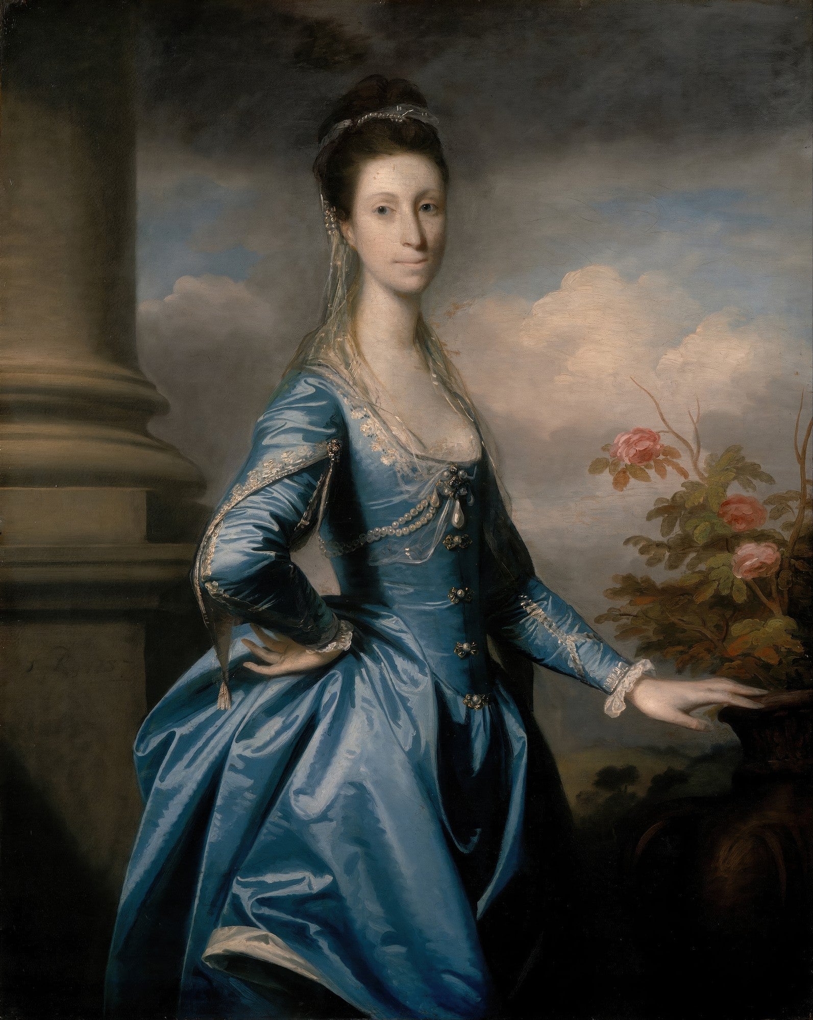 Retrato de uma senhora em vestido azul de seda, com um véu e joias, atribuído a Sir Joshua Reynolds. Ela está em pé ao lado de uma coluna clássica e um vaso de flores, com um céu nublado ao fundo.