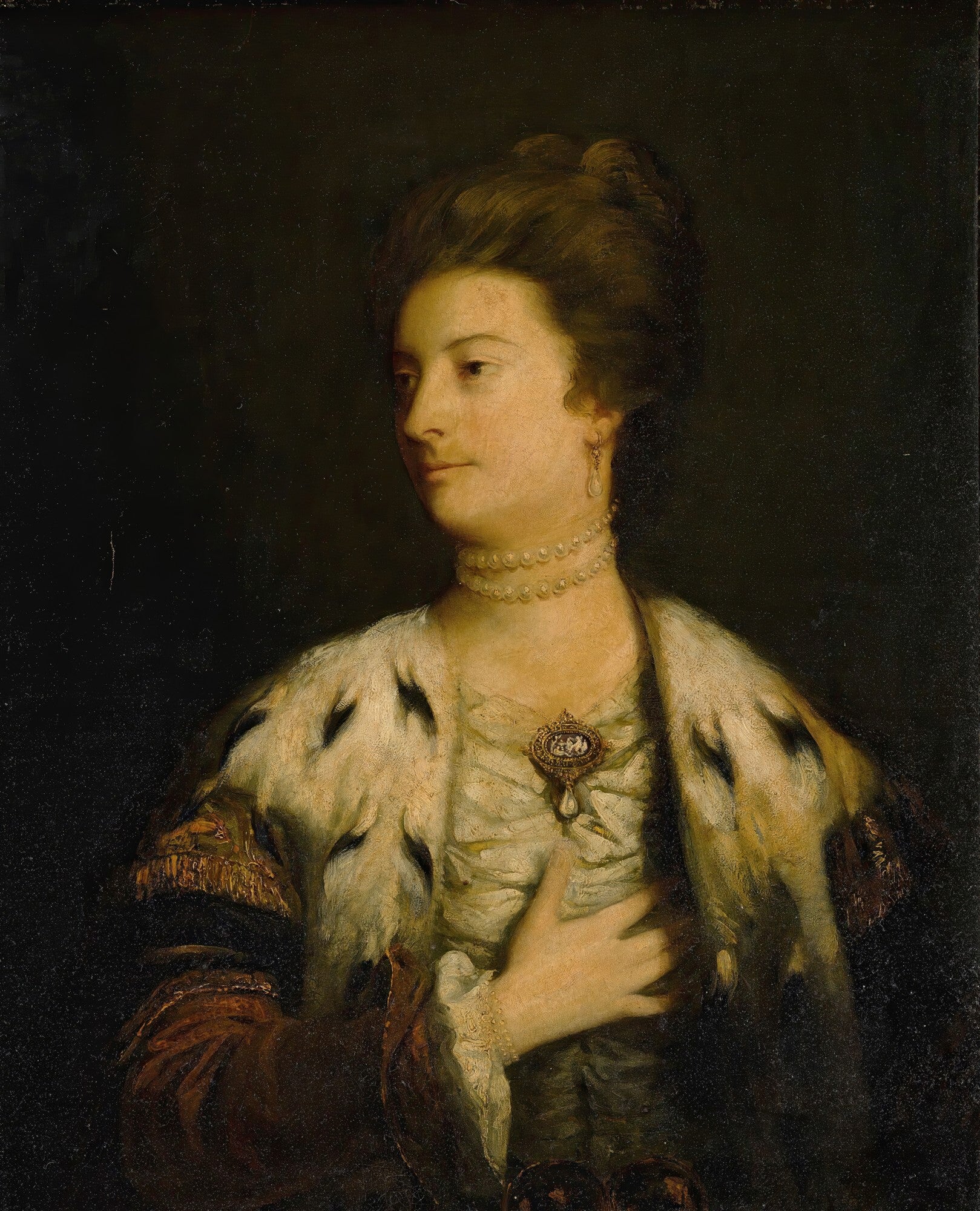 Retrato de uma mulher de feições gentis, com um colar de pérolas e um casaco de pele de arminho, sobre um fundo escuro, atribuído a Sir Joshua Reynolds.