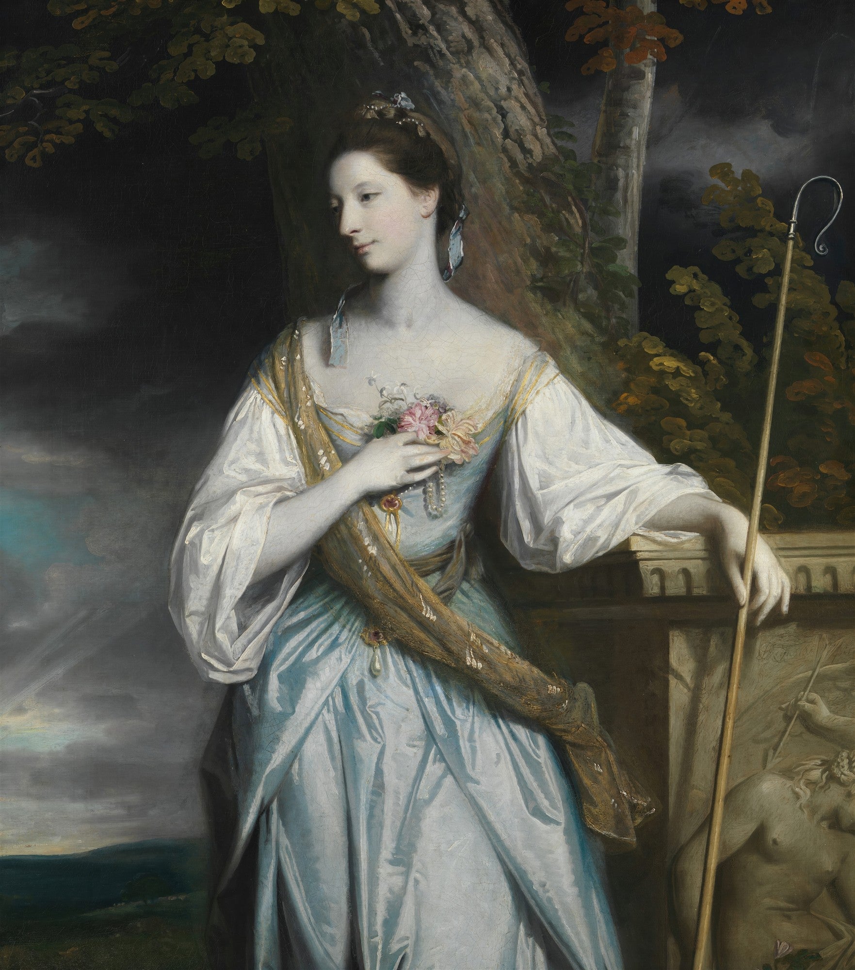 Retrato de uma mulher elegante em vestido azul e branco, segurando um cajado, com um cenário de natureza ao fundo, atribuído a Sir Joshua Reynolds.