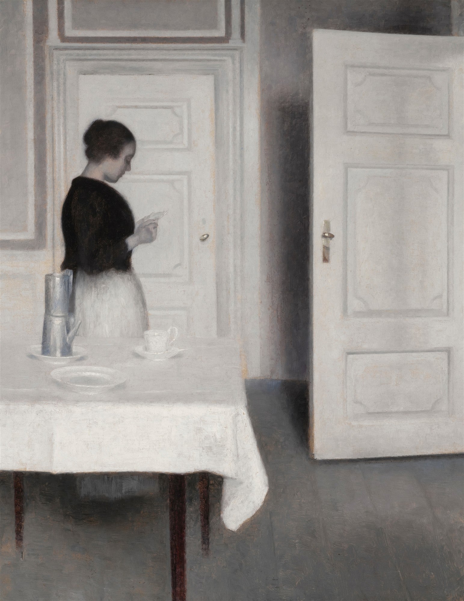 Quadro decorativo com uma mulher de costas, lendo uma carta em um interior com portas brancas e uma mesa posta. A paleta de cores é predominantemente cinza e branco, com detalhes em preto e marrom. A luz suave ilumina a cena, criando uma atmosfera melancólica e introspectiva, característica do estilo de Vilhelm Hammershøi.