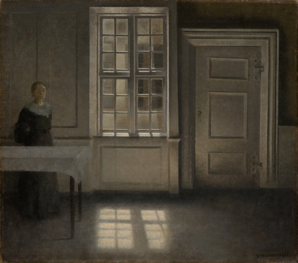 Quadro decorativo de Vilhelm Hammershøi. Interior com mulher de costas, mesa e janela grande que projeta luz no chão, em tons de cinza e marrom.