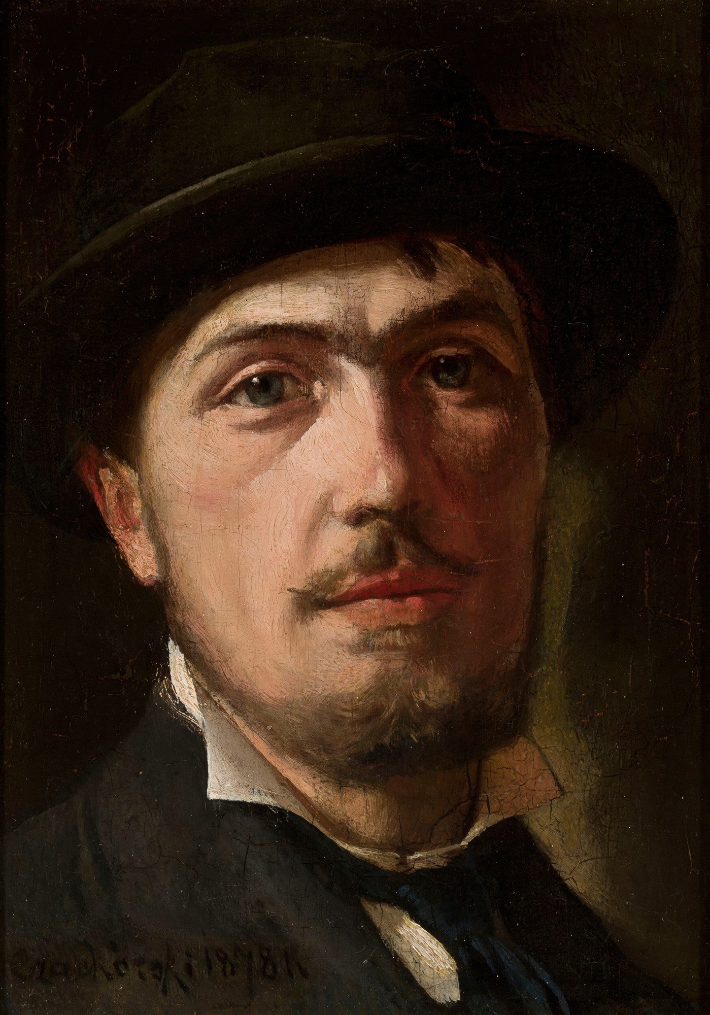 Autorretrato de Wladyslaw Czachórski, um homem com bigode e cavanhaque, usando um chapéu escuro e terno, com um olhar penetrante e sério. A iluminação destaca um lado do rosto e os olhos.